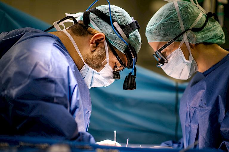 Bild eines Arztes während einer Herzuntersuchung und ein Bild mit Fokus auf die Vergößerungsgläser über der Brille eines Arztes