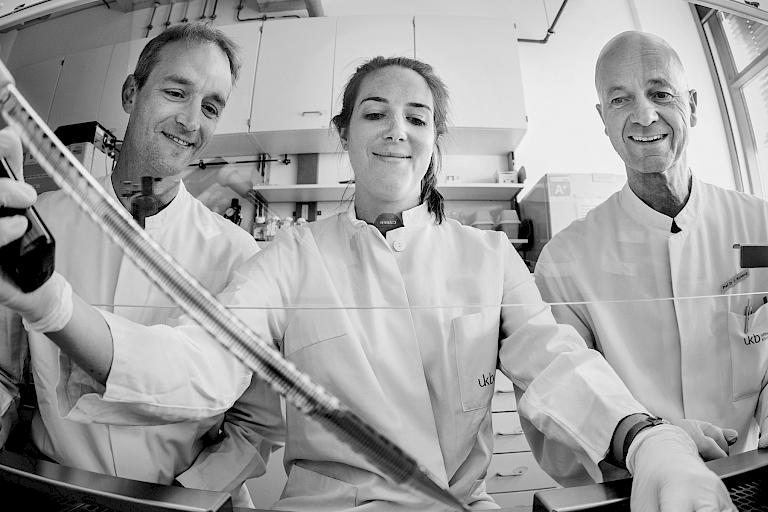 Drei Forscher des Herzzentrums bei der Arbeit mit einer Pipette und ein Bild einer Maschine mit mehreren Pipetten