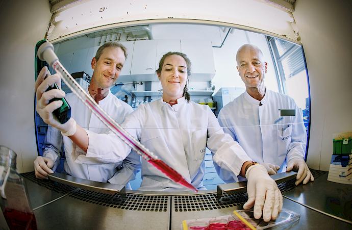 Drei Forscher des Herzzentrums in Laborkitteln schauen lächelnd in die Kamera